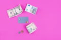 Money of different currencies and nominal plastic card on a pink background