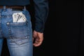 Money dollars and a condom in the back pocket of men`s jeans Royalty Free Stock Photo