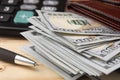 Money dollars, purse, pen and calculator on a wooden table. Close-up. Royalty Free Stock Photo