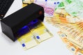 Money fake testing - euro banknotes authentication check in UV Currency Detector lights. Counterfeiting banknotes, checking at the Royalty Free Stock Photo