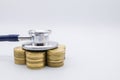 Money, Finance and Health Care concept. Close up of  stethoscope on top of row of stack of gold coins on white background and copy Royalty Free Stock Photo