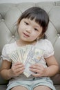 Money, finances and people concept - smiling little girl looking at dollar cash money