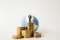 Money and Global Business Concept. Businessman miniature figure people standing on stack of gold coins and mini world ball as