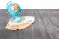 Money and globus on grey wooden desk. Euro money under globe of world. Copy space for text. Travel and money concept