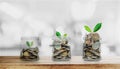 Money growing concepts, bottle of coins increasing with plants on wooden table and Bokeh background