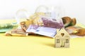 Money, house and a moneybox on a yellow background. Savings, mortgage, family budget concept. Copy space Royalty Free Stock Photo