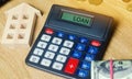 Money and houses on the table and a calculator with the word Loan. The concept of buying property in debt. Analysis of costs and Royalty Free Stock Photo