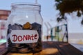 money jar with a label with the word donations on it and wooden,outside photo on donate written jar Royalty Free Stock Photo