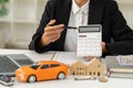 Money, keys and a small wooden house on the table, orange car and laptop. blurry background in the office The concept of leasing i Royalty Free Stock Photo