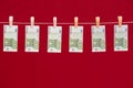 Money laundering, euro banknotes hanging on rope over red studio background. Royalty Free Stock Photo