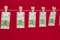Money laundering, euro banknotes hanging on rope over red studio background. Royalty Free Stock Photo