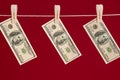 Money laundering, US dollars hanging on rope over red studio background