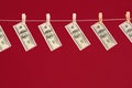 Money laundering, US dollars hanging on rope over red studio background