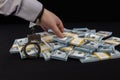 The money lies on a black background, and the hand of a man in a shirt with handcuffs reaches out to it. A man& x27;s Royalty Free Stock Photo