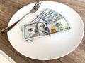 Money lying on the plate with fork. Dollars photo. Greedy corruption concept. Bribe idea