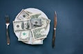 Money lying on the plate with fork and knife. Dollars photo. Greedy corruption concept. Bribe idea