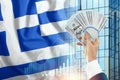 Money in a man`s hand against the background of the flag of Greece. The income of the Greeks. The financial condition of the