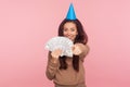 This money may be yours! Portrait of optimistic woman with party cone on head pointing at camera and holding dollars