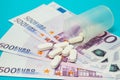 Money pills. Medicine pills on euro bills on a blue background. Covid-19 coronavirus pills are in euro money. The