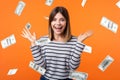 Money rain. Portrait of amazed beautiful young woman with brown hair in long sleeve striped shirt standing, raising hands, looking Royalty Free Stock Photo