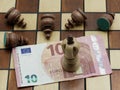 Money Rules Concept: King Chess Piece On 10 Euro Banknote With Defeated Pawns