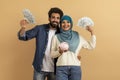 Money Saving. Happy Muslim Couple Holding Piggybank And Dollar Cash In Hands Royalty Free Stock Photo