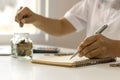 Money saving idea. A woman`s hand holding a pen to jot down expenses Royalty Free Stock Photo