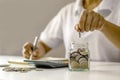 Money Saving Ideas for Financial Accounting, Young lady `s hand is putting coins in a jar. Royalty Free Stock Photo