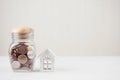 Money of savings coins in glass jar with model white house on wooden table. Property investment and house mortgage financial Royalty Free Stock Photo