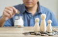 Money savings concepts Family wooden dolls on coins with blur Men are coining in Glass bottel for saving money for families with
