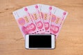 Money transfer with smart phone, Chinese yuan on wooden background with smartphone. Royalty Free Stock Photo