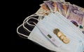 Money of United Kingdom close up on black background. Pounds UK 10 and 20 note face mask and thermometer Royalty Free Stock Photo