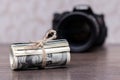 Money US dollars in a roll tied with a rope near the camera. Salary for the work of a photographer Royalty Free Stock Photo