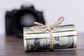 Money US dollars in a roll tied with a rope near the camera. Salary for the work of a photographer Royalty Free Stock Photo