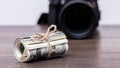 Money US dollars in a roll tied with a rope near the camera. Salary for the work of a photographer Royalty Free Stock Photo