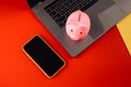 Moneybox near laptop and smartphone, place for text. Finance and budget concept. Piggy bank in pink color with gadgets