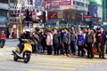 Mong Kok street corner: Motorbike turns, pedestrians wait to cross
