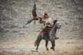 Mongolia, Golden Eagle Festival.Hunter On A Gray Horse With A Magnificent Golden Eagle, Spreading His Wings And Holding Its Prey.