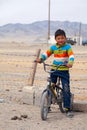 Mongolia Ulgii 2019-05-05 Mongolian boy with bike in colorful clothes stand near fence of barbed wire in steppe on