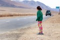 Mongolia Ulgii 2019-05-05 Mongolian girl in colorful clothes stands on the road and looks after leaving car. Concept
