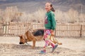 Mongolia Ulgii 2019-05-05 smiling Mongolian girl in colorful clothes with a dog Caucasian shepherd on background of