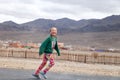 Mongolia Ulgii 2019-05-05 smiling Mongolian girl in colorful clothes is running on background of fence, village