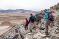 Mongolia Ulgii 2019-05-04 Tourist group in colored clothes with backpacks hiking, climbing together with guide, coming down from