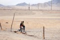 Mongolia Ulgii 2019-05-05 Two Mongolian boys with bike in colorful clothes stand near fence of barbed wire in steppe on