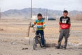 Mongolia Ulgii 2019-05-05 Two Mongolian boys in colorful clothes stand near fence of barbed wire in steppe on background