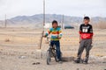 Mongolia Ulgii 2019-05-05 Two Mongolian boys in colorful clothes stand near fence of barbed wire in steppe on background