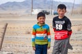 Mongolia Ulgii 2019-05-05 Two Mongolian boys in colorful clothes stand near fence of barbed wire in steppe on background