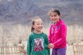 Mongolia Ulgii 2019-05-05 Two smiling Mongolian girls in colorful clothes on background of fence, mountains. Concept of