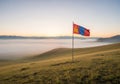 A Mongolian flag flutters on a gently sloping grassy hillside under a clear sky. The landscape Royalty Free Stock Photo