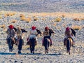 Mongolian Golden Eagle Hunter in traditional clothing riding on horseback to the Golden Eagle Hunter Festival competition site at